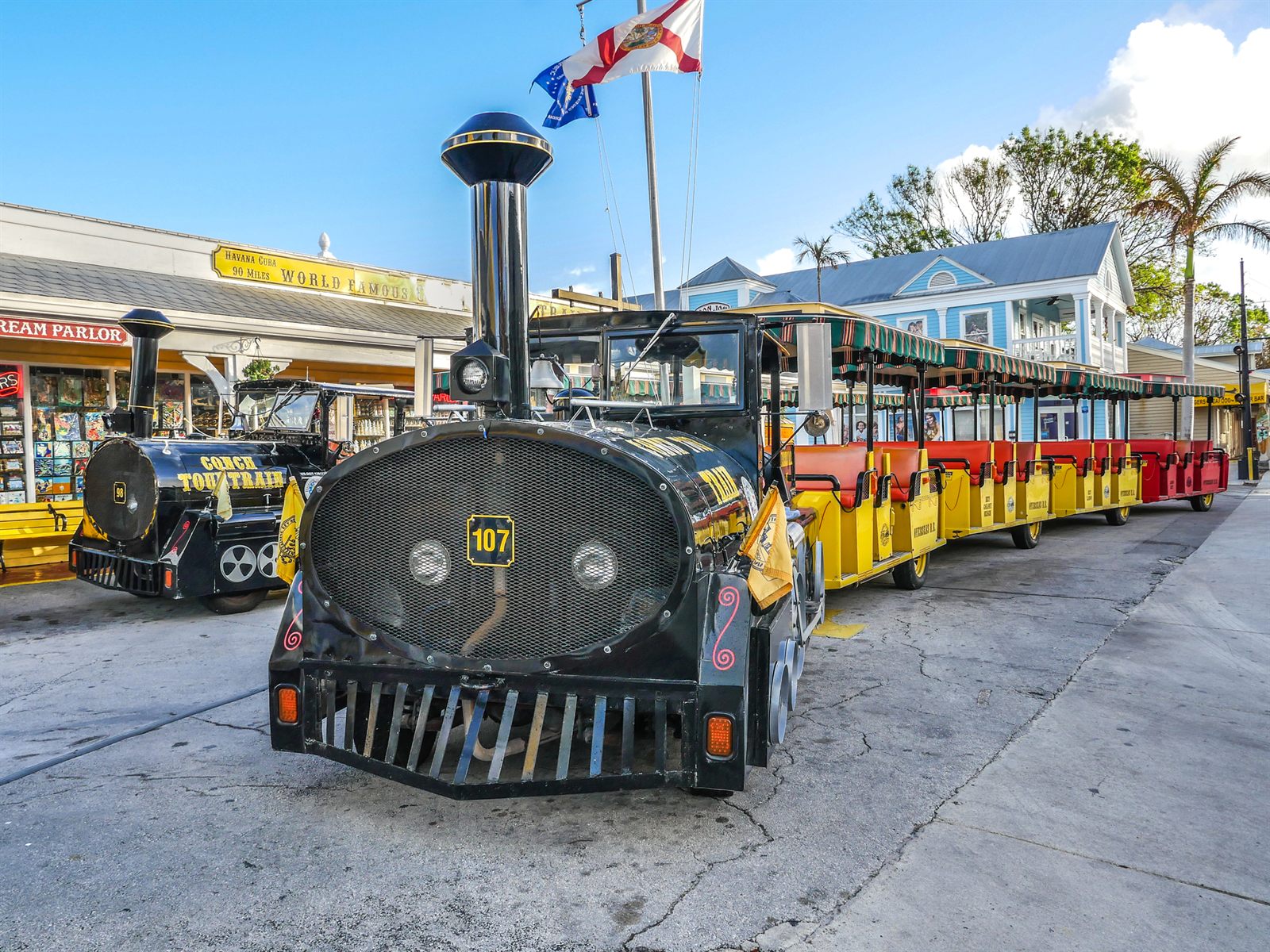 Open-air sightseeing tram with a locomotive-style engine parked on a sunny street, a tour product covered in travel industry training